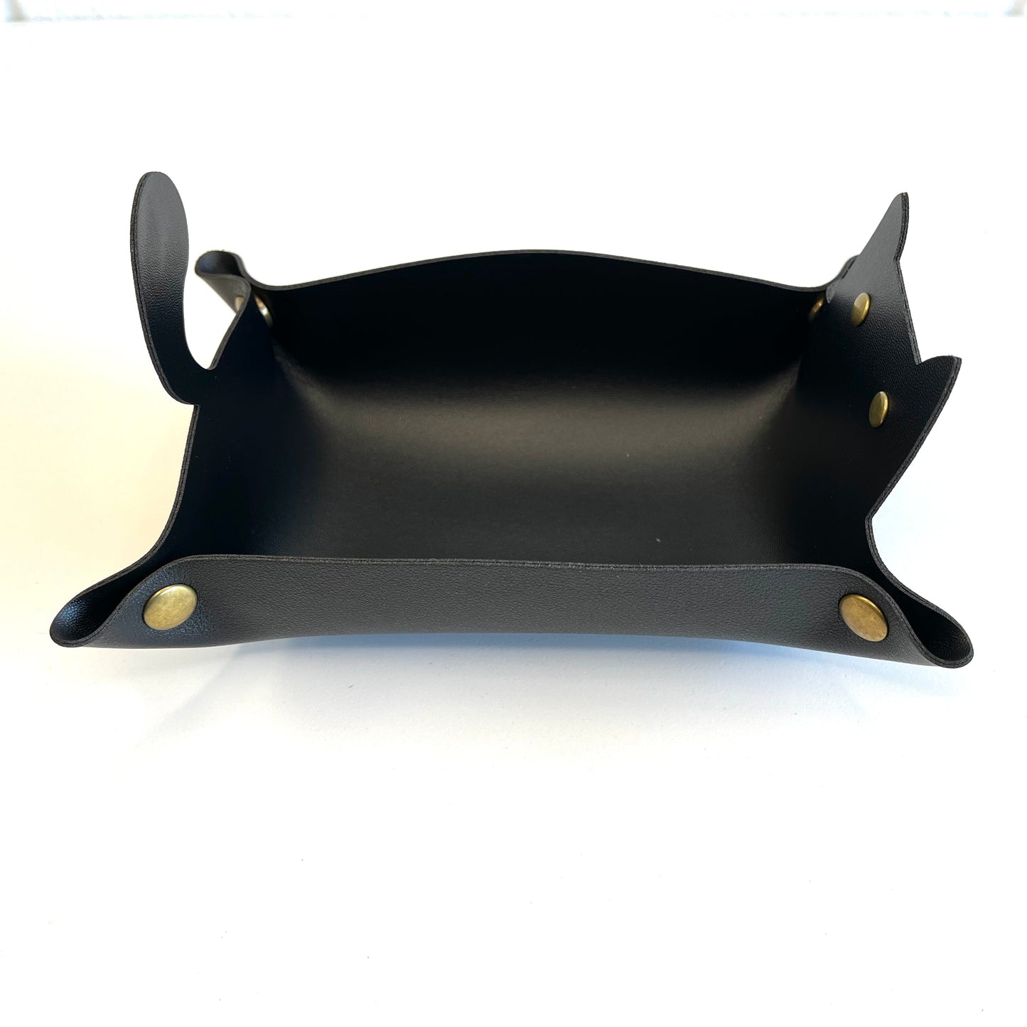 A black leather cat dice tray with integrated handles and brass snap buttons, shown on a plain white background.