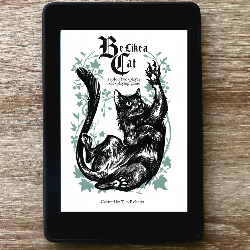 A black tablet device lying on a light brown wood surface, displaying a book or play cover titled "Be Like a Cat" with a black cat illustration on the screen.