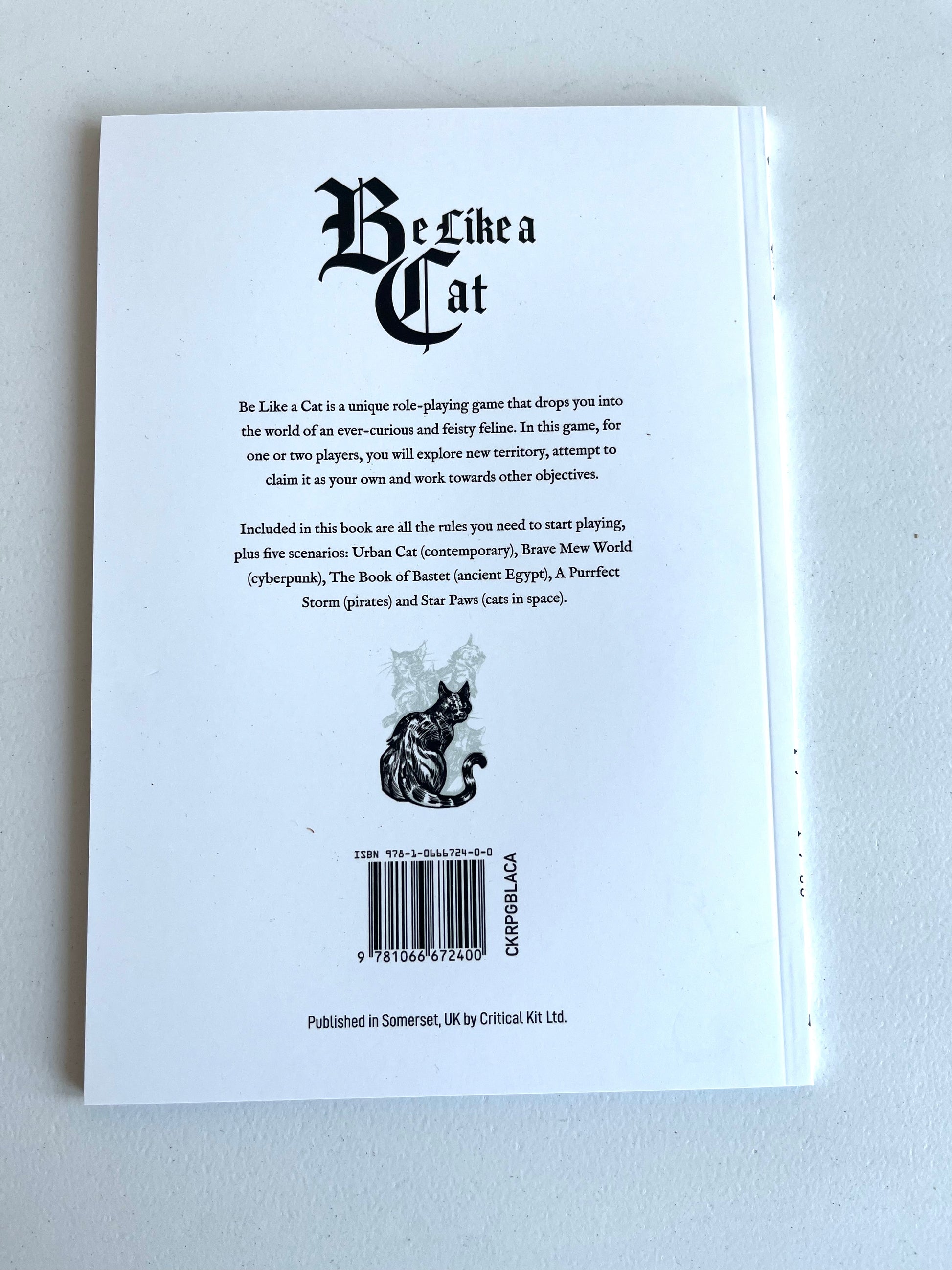 The back cover of the book 'Be Like a Cat' by Critical Kid, featuring black gothic-style typography, a black cat illustration, and a barcode on a white background.