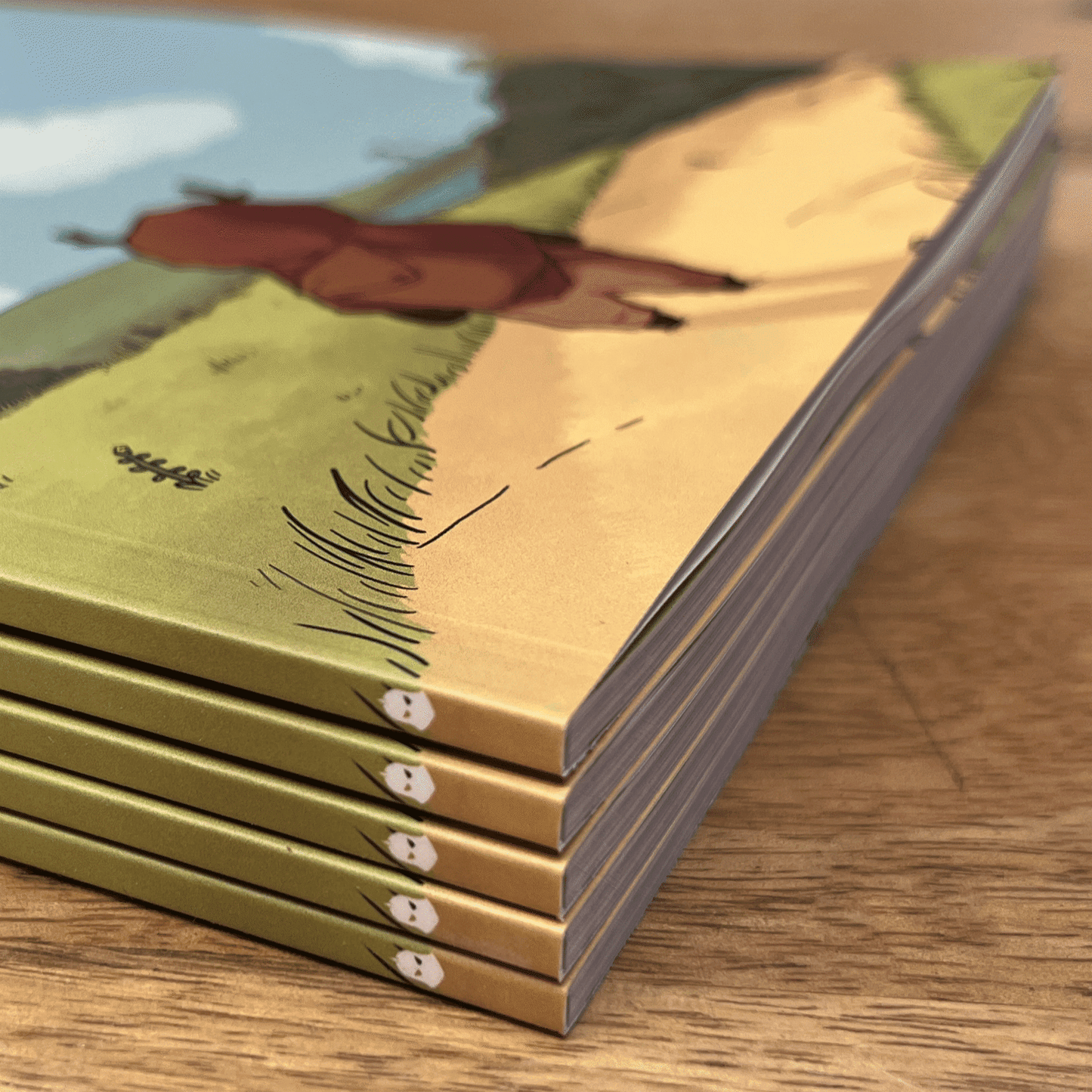 Stack of books with a bear illustration on the cover, placed on a wooden surface.