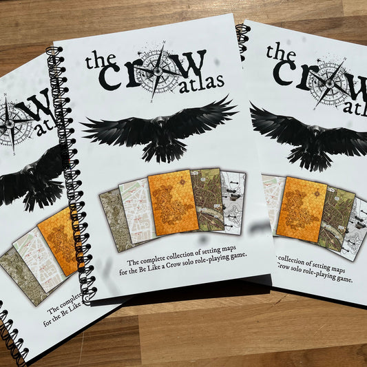 Two copies of 'The Crow Atlas' on a wooden surface