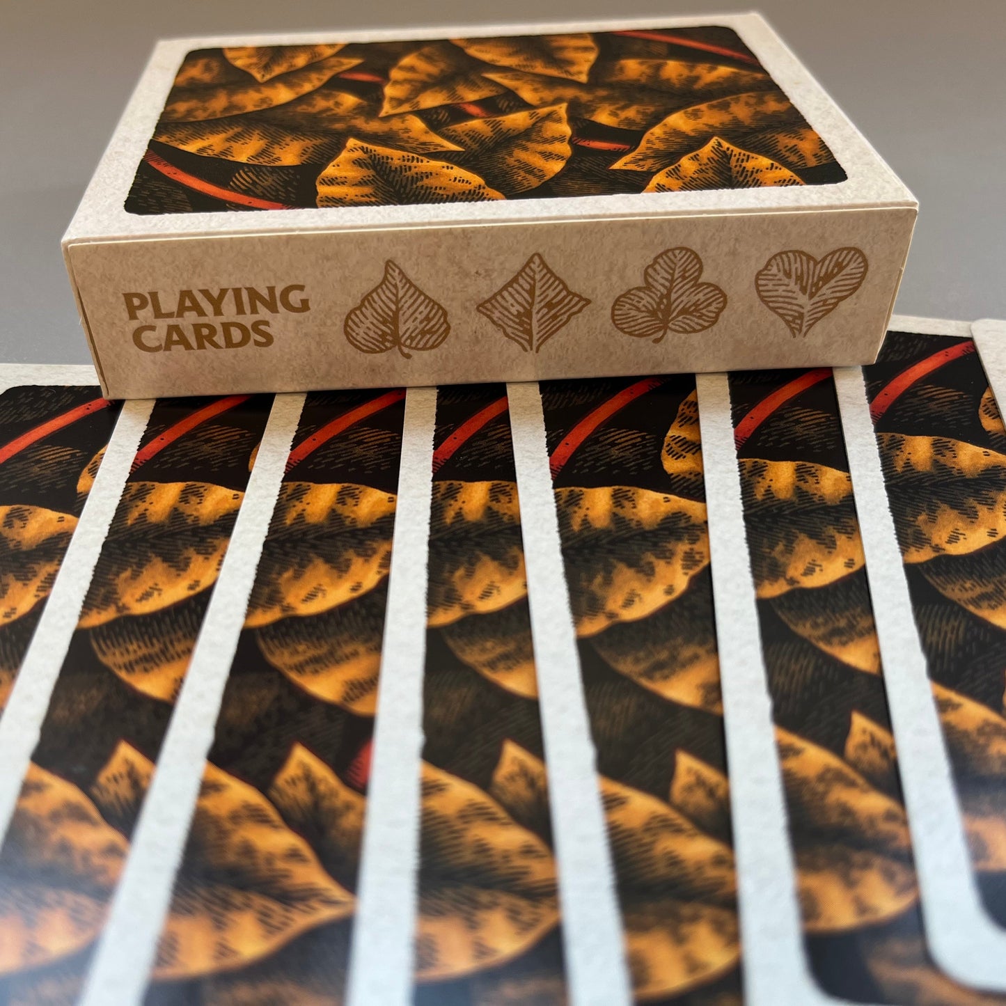 A deck of wires in the woods playing cards showing the autumnal decorated backs of the cards and the box spine with the suits drawn as leaves