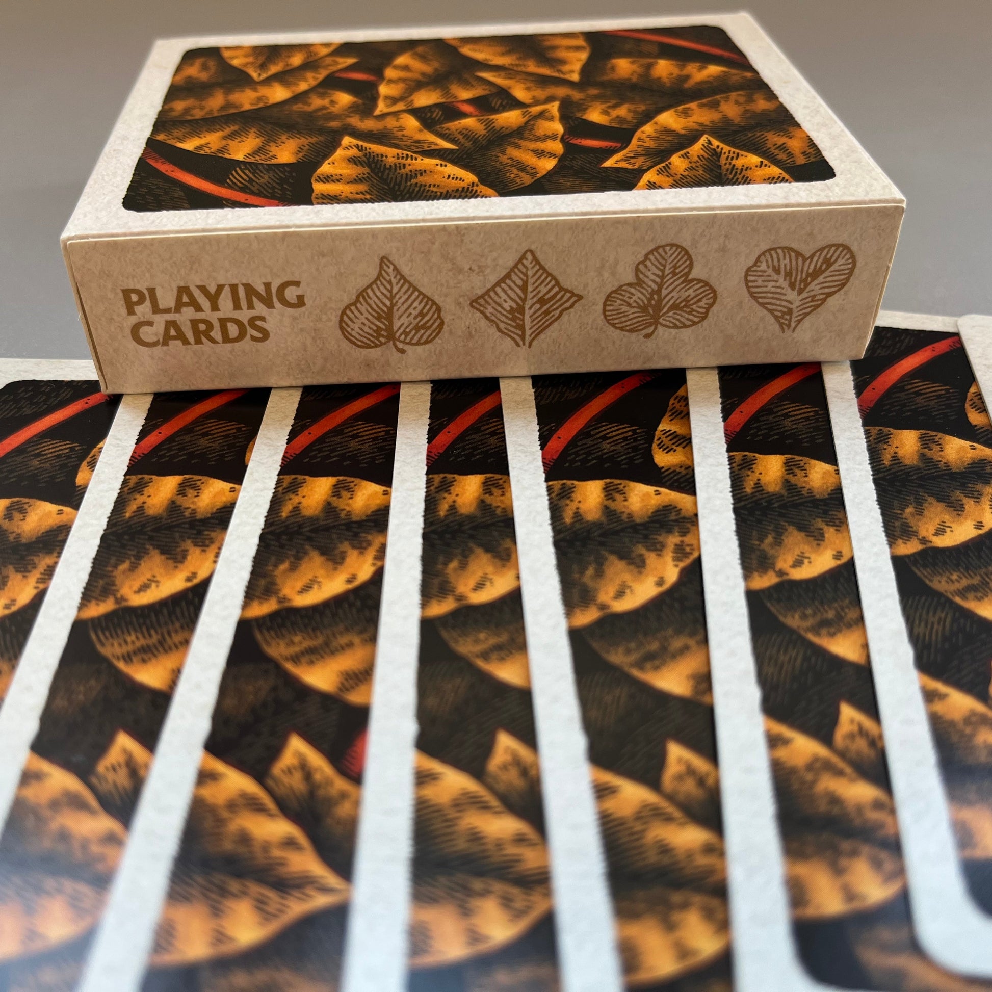 A deck of wires in the woods playing cards showing the autumnal decorated backs of the cards and the box spine with the suits drawn as leaves