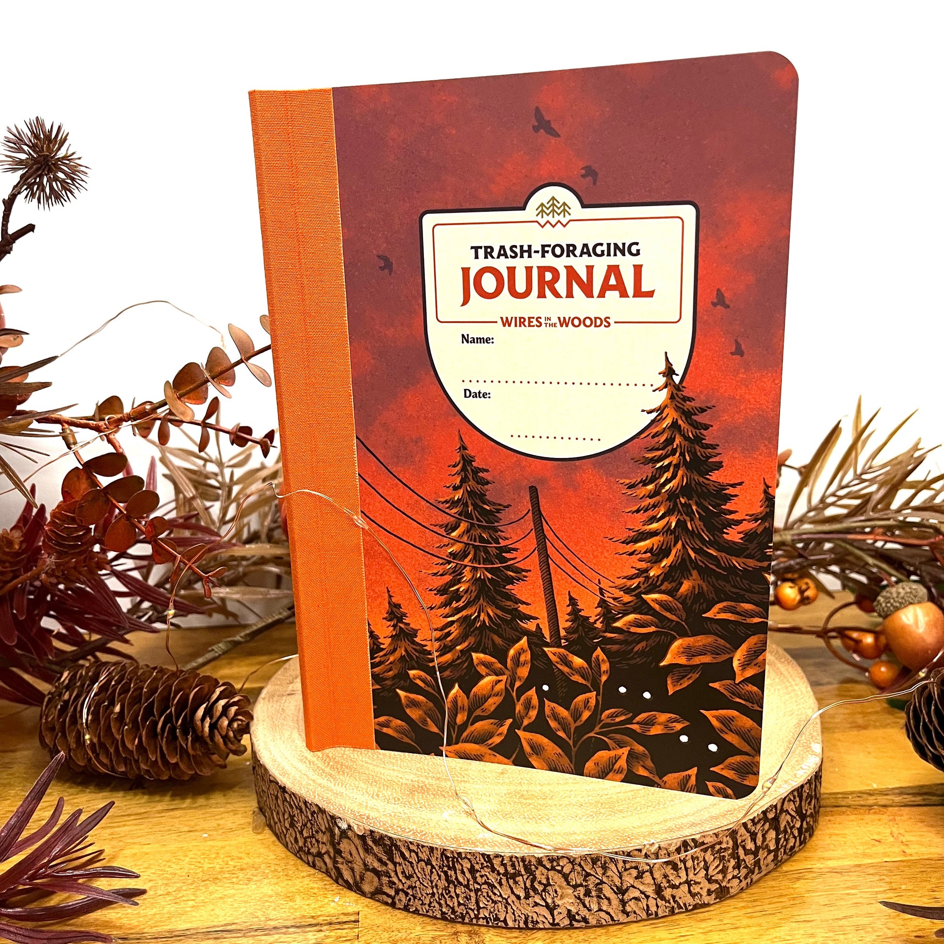 Wires in the Woods journal stood on a wood stand with autumnal follage